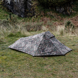 Highlander Blackthorn 1+ Tent Gen2 in HMTC Camo - pitched on grassland below a rocky crag