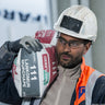 Bolle Contour Safety Glasses with clear lens worn by a construction worker in a white hard hat and hi-vis carrying a bag of screed
