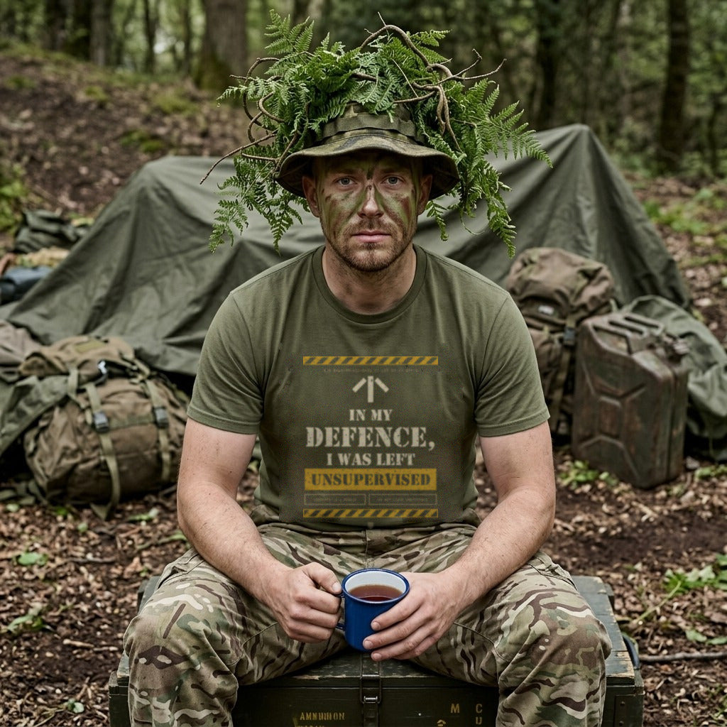 Man in Military Green "Unsupervised" T-shirt with fern-covered hat and face paint, holding a mug of tea on a crate