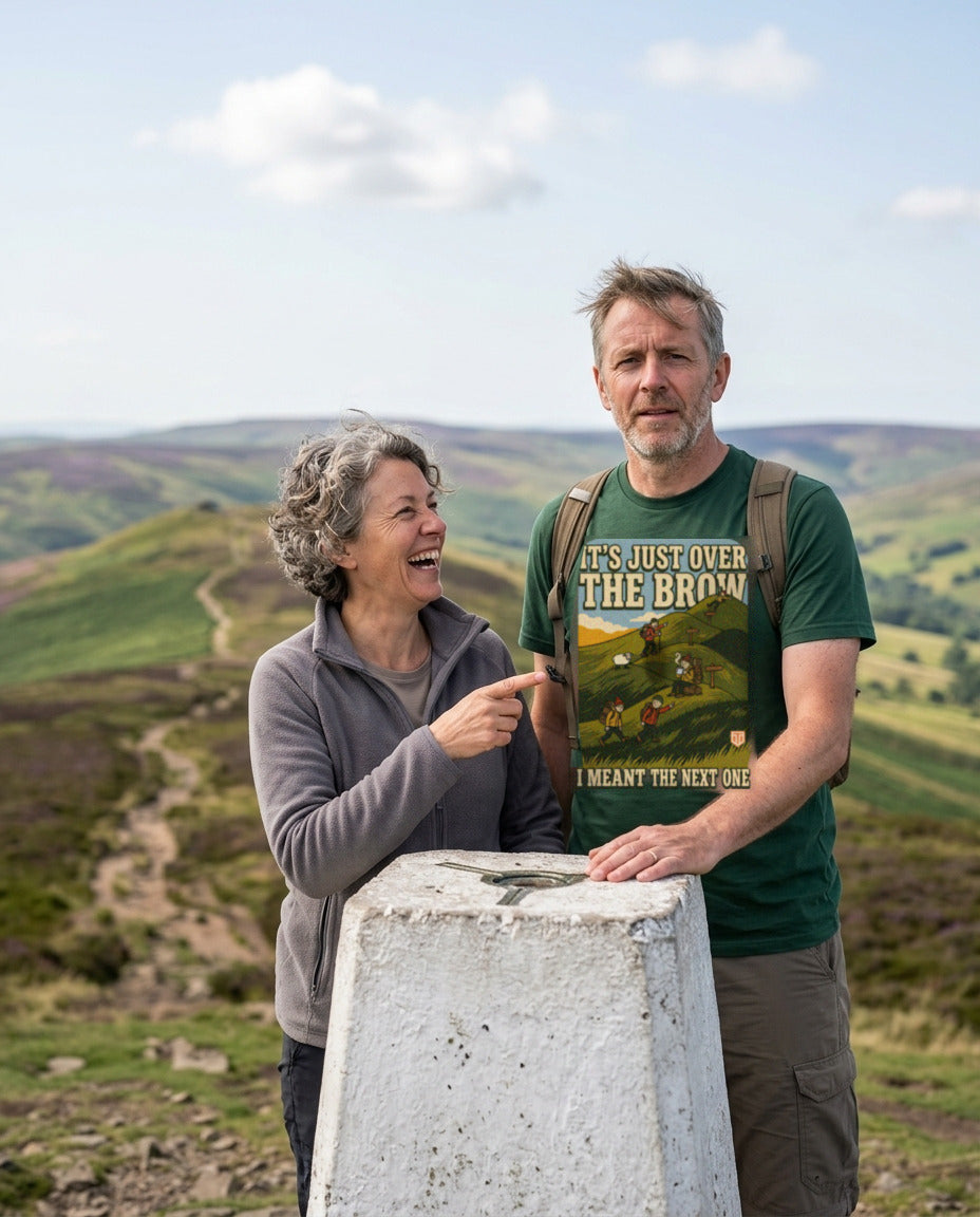 Couple at a trig point on a hill summit, the man wearing the It's Just Over the Brow T-Shirt in Forest