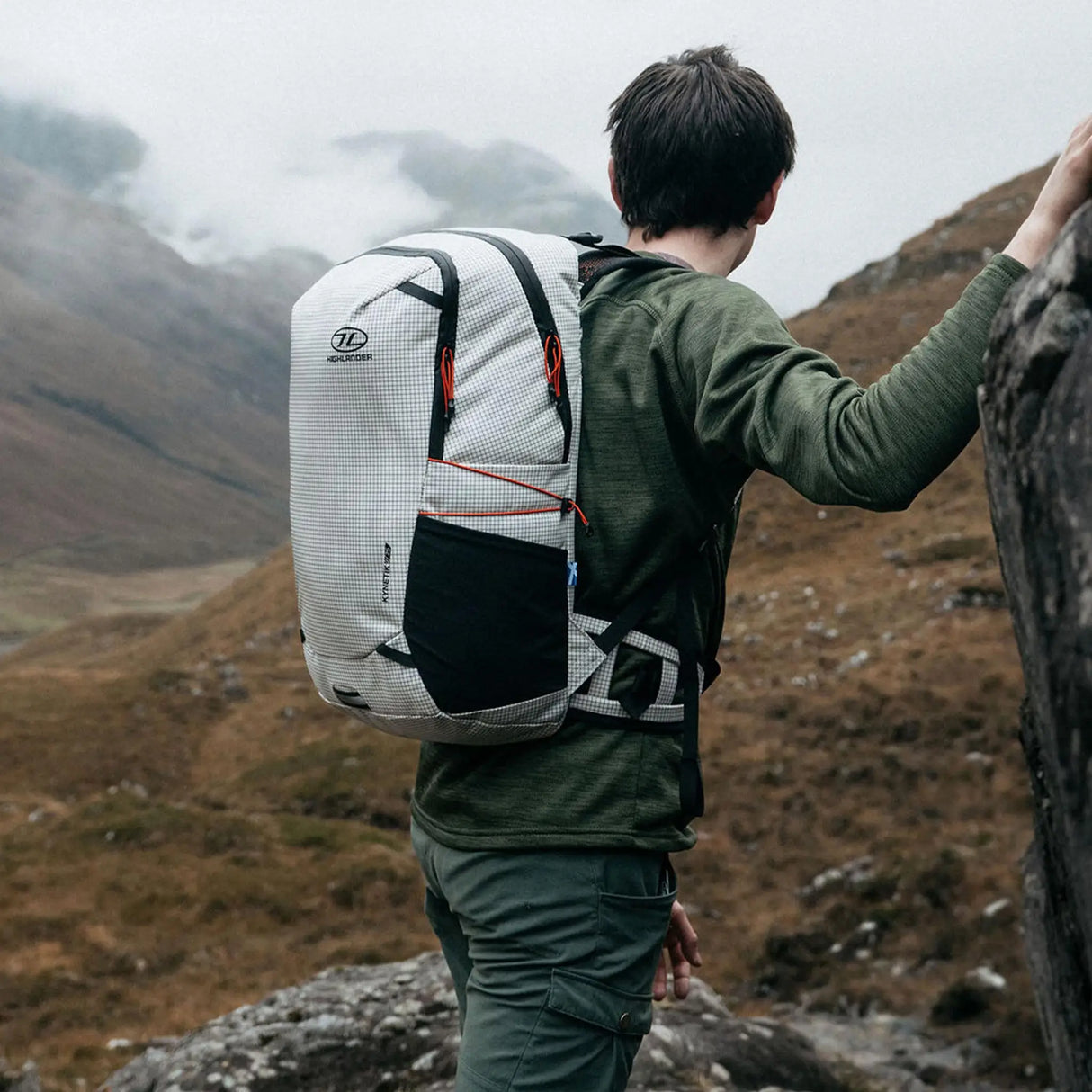 Highlander Kynetik Rucksack 25L in White - worn by a hiker resting against a rock in a misty Scottish glen