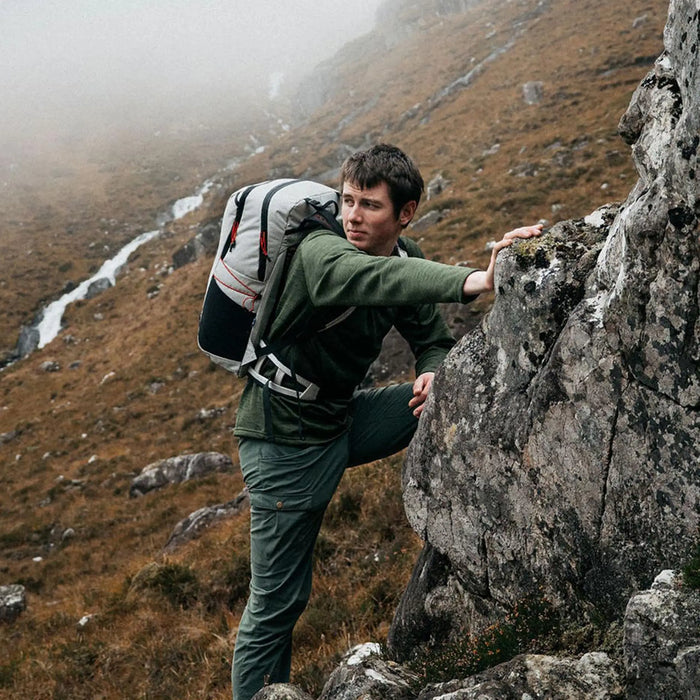 Highlander Kynetik Rucksack 25L in White - worn by a hiker scrambling up rock above a hill burn
