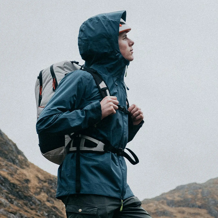 Highlander Kynetik Rucksack 25L in White - worn by a hiker fastening a jacket below a cloud-covered hillside