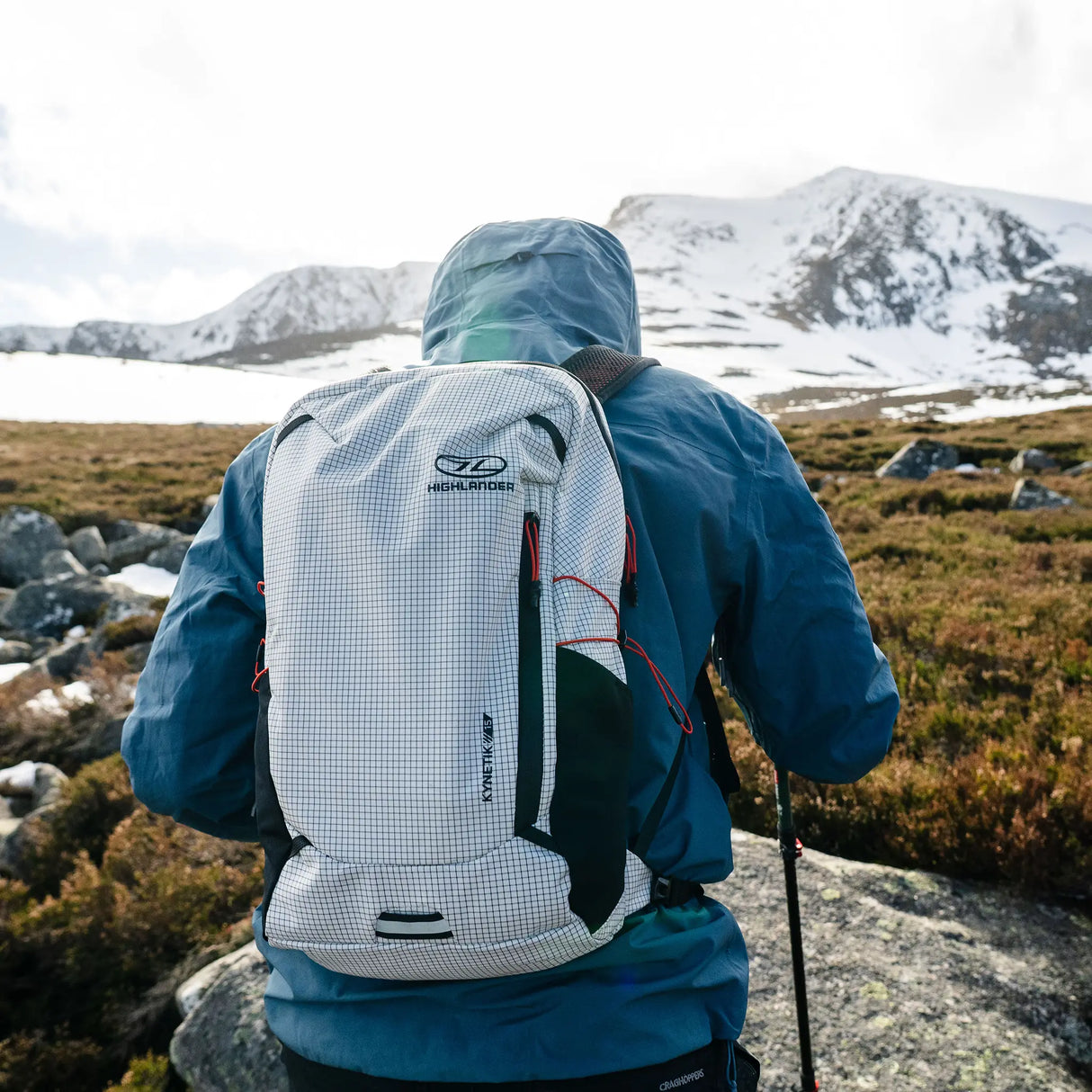 Highlander Kynetik Rucksack 15L in White - worn by a hiker with a walking pole below a snow-covered peak