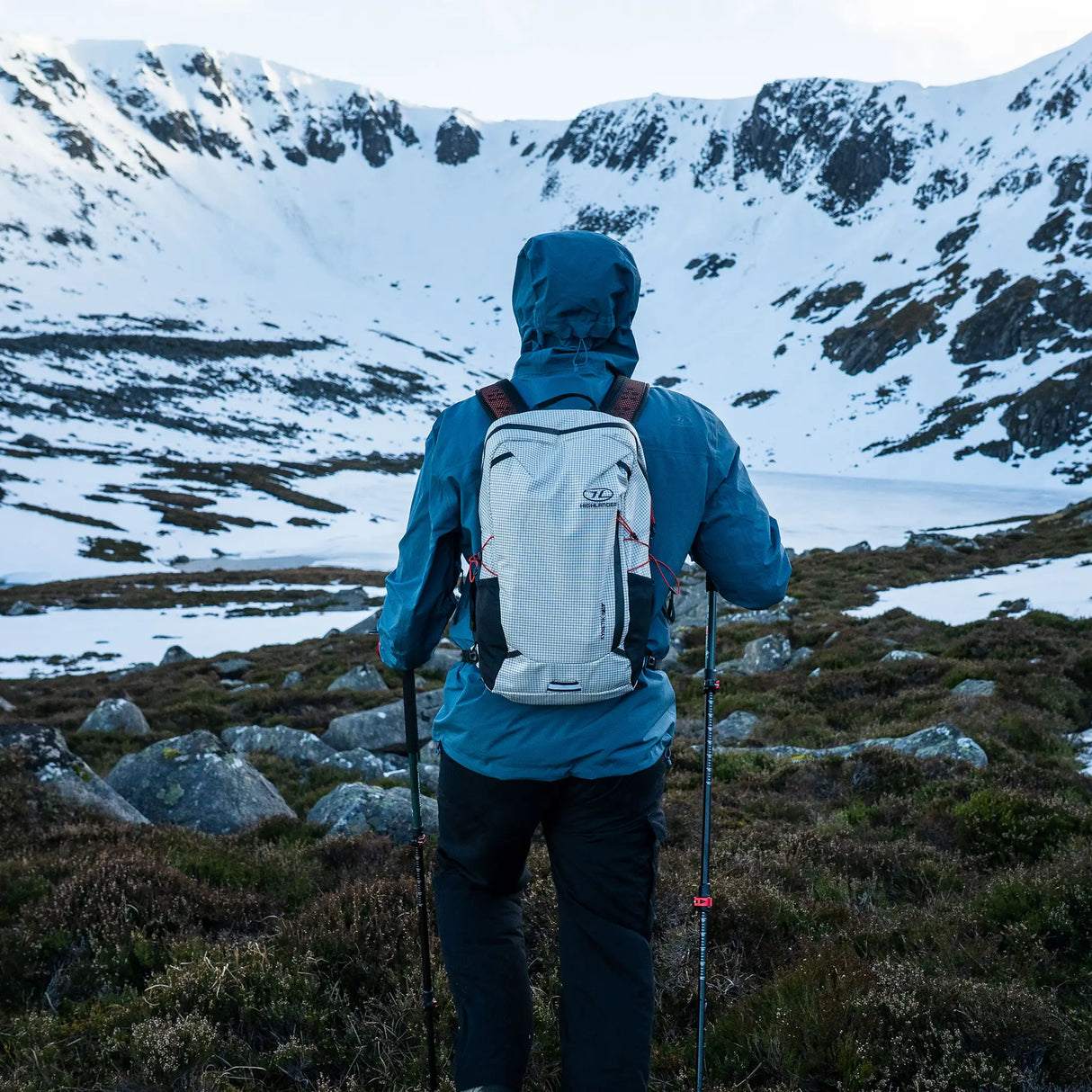 Highlander Kynetik Rucksack 15L in White - worn by a hiker with trekking poles above a frozen lochan