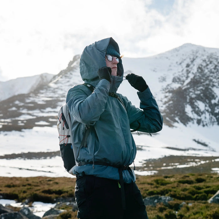 Highlander Kynetik Rucksack 15L in White - worn by a hiker adjusting a jacket hood below a snowy mountain