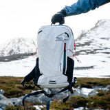 Highlander Kynetik Rucksack 15L in White - held by the grab handle in front of a snowy corrie
