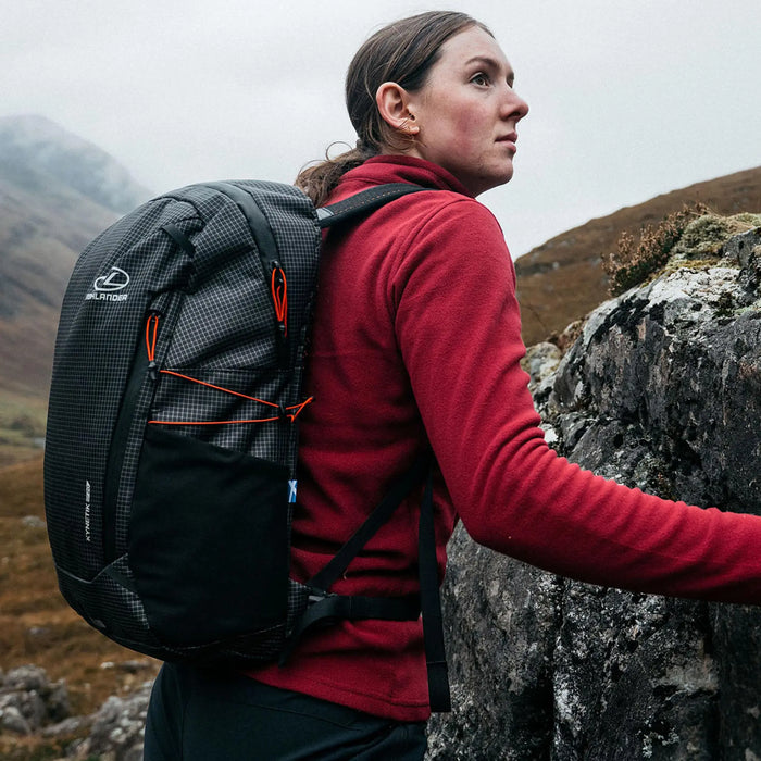 Highlander Kynetik Rucksack 20L in Black - worn by a hiker resting against a rock on a misty hillside
