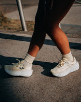 Runner walking on a sunlit tarmac path in pale cream socks and cream running shoes