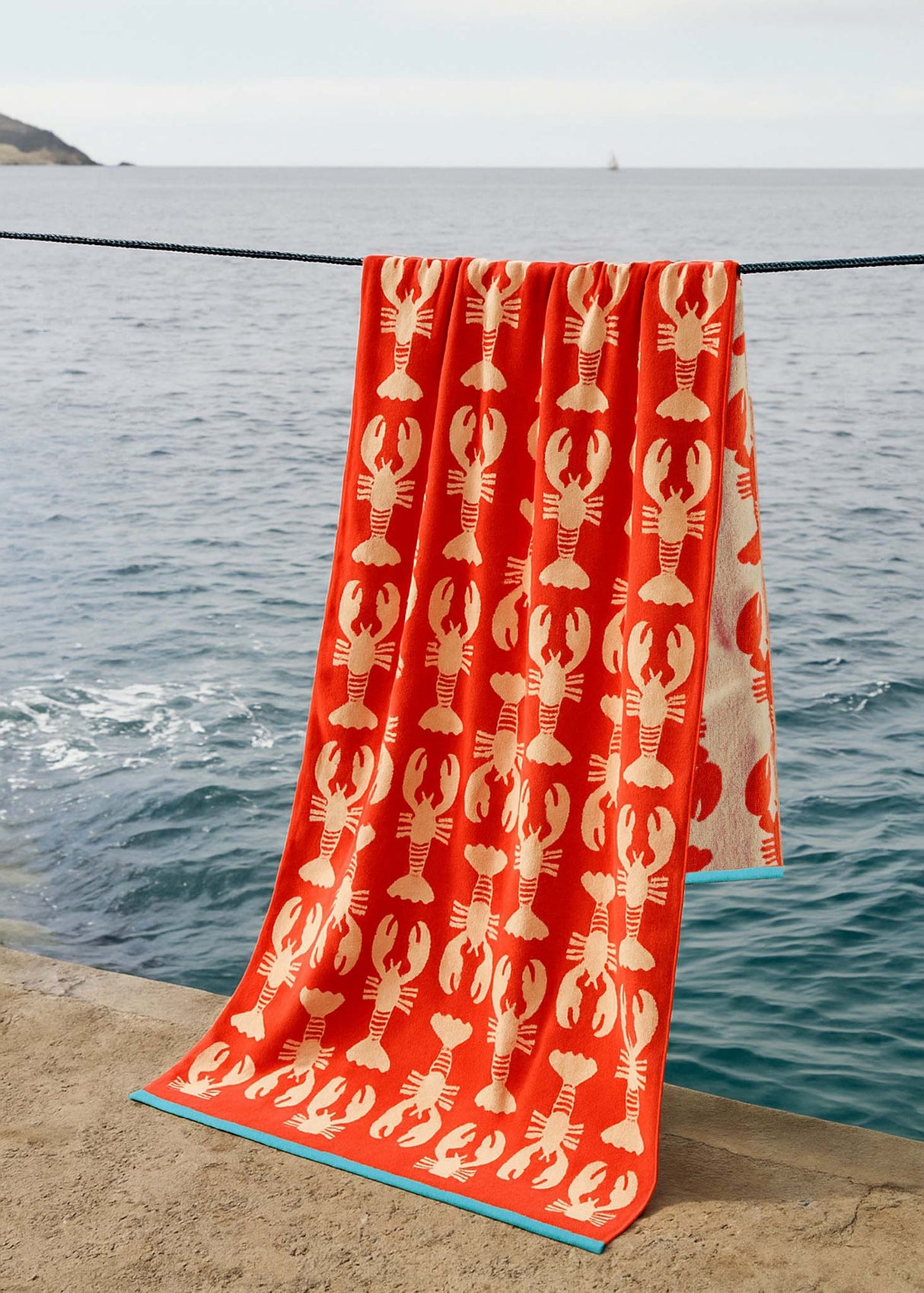 Anorak Lobsters Organic Cotton Towel - Coral and pink hanging by the sea
