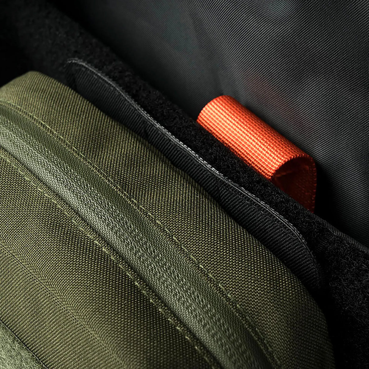 Detail inside a Stoirm pack showing an Olive Green Eco-System pouch seated against the black hook and loop lining where the Large MOLLE Panel mounts