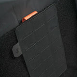 Stoirm Large MOLLE Panel in Black mounted on the hook and loop lining inside a Stoirm pack, showing the laser-cut slots and the Stoirm pull tab