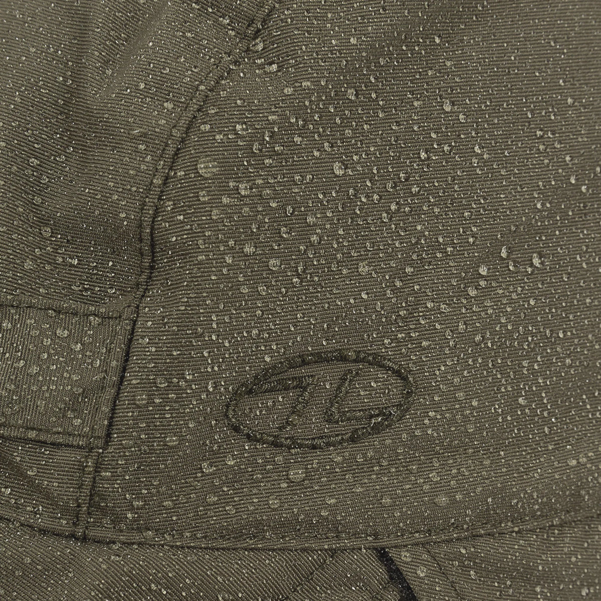 Highlander Waterproof Mountain Hat - close-up of water beading on the Ranger Green waterproof fabric beside the embroidered logo