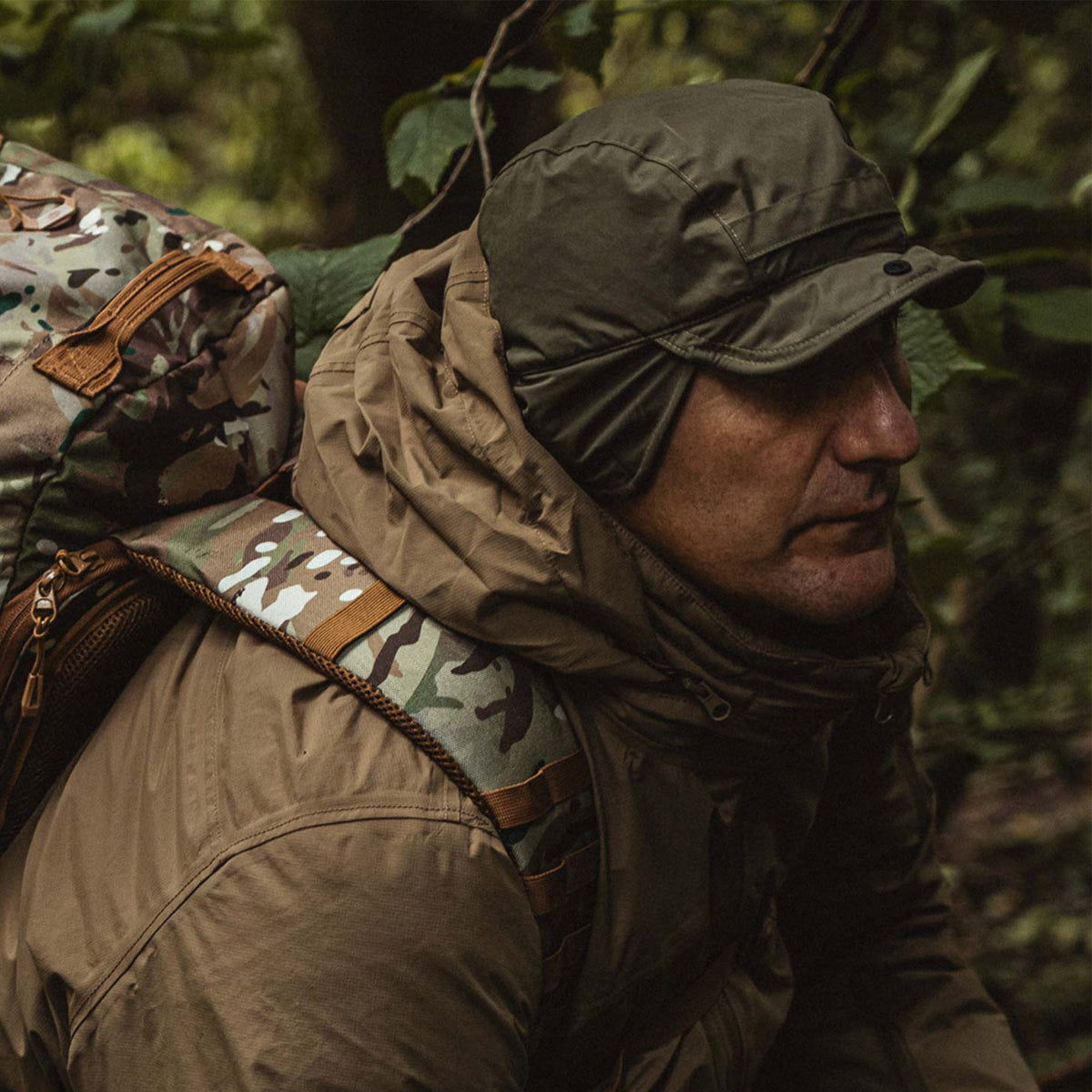 Highlander Waterproof Mountain Hat - worn in Ranger Green with the ear flaps down while hiking through woodland with a rucksack