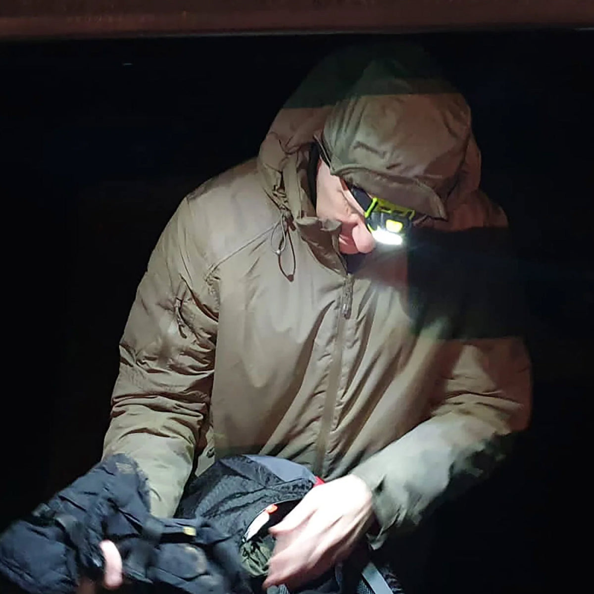 Highlander Waterproof Mountain Hat - side view worn in woodland with the wearer holding the peak and hood down
