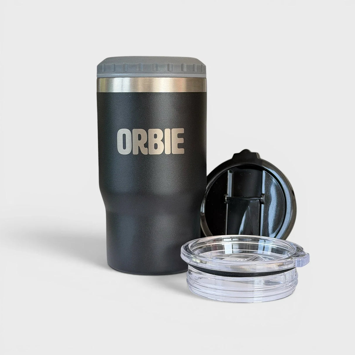 Orbie 12oz insulated cup in black with the grey can cooler collar fitted, beside the flip-top and sliding sip lids