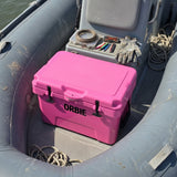 Pink Orbie 35 cool box in an inflatable boat beside fishing tackle, gloves and rope