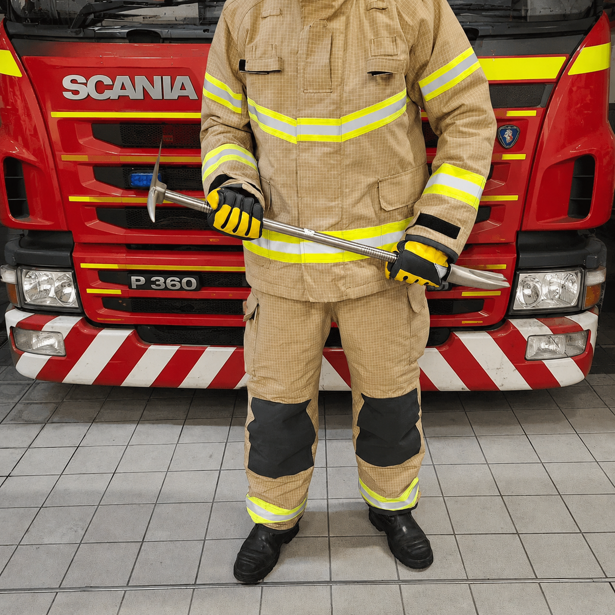 Firefighter in tunic holding the Hooligan Bar in front of a fire engine