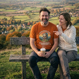 Couple laughing on a hilltop bench above autumn fields, the man wearing the Sloth Hiking Club: Hilltop T-Shirt in Autumn