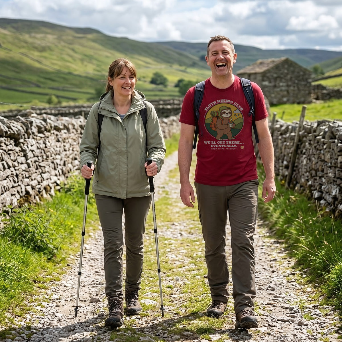 Couple laughing on a Yorkshire Dales walled lane, the man wearing the Sloth Hiking Club: Walking T-Shirt in Cardinal