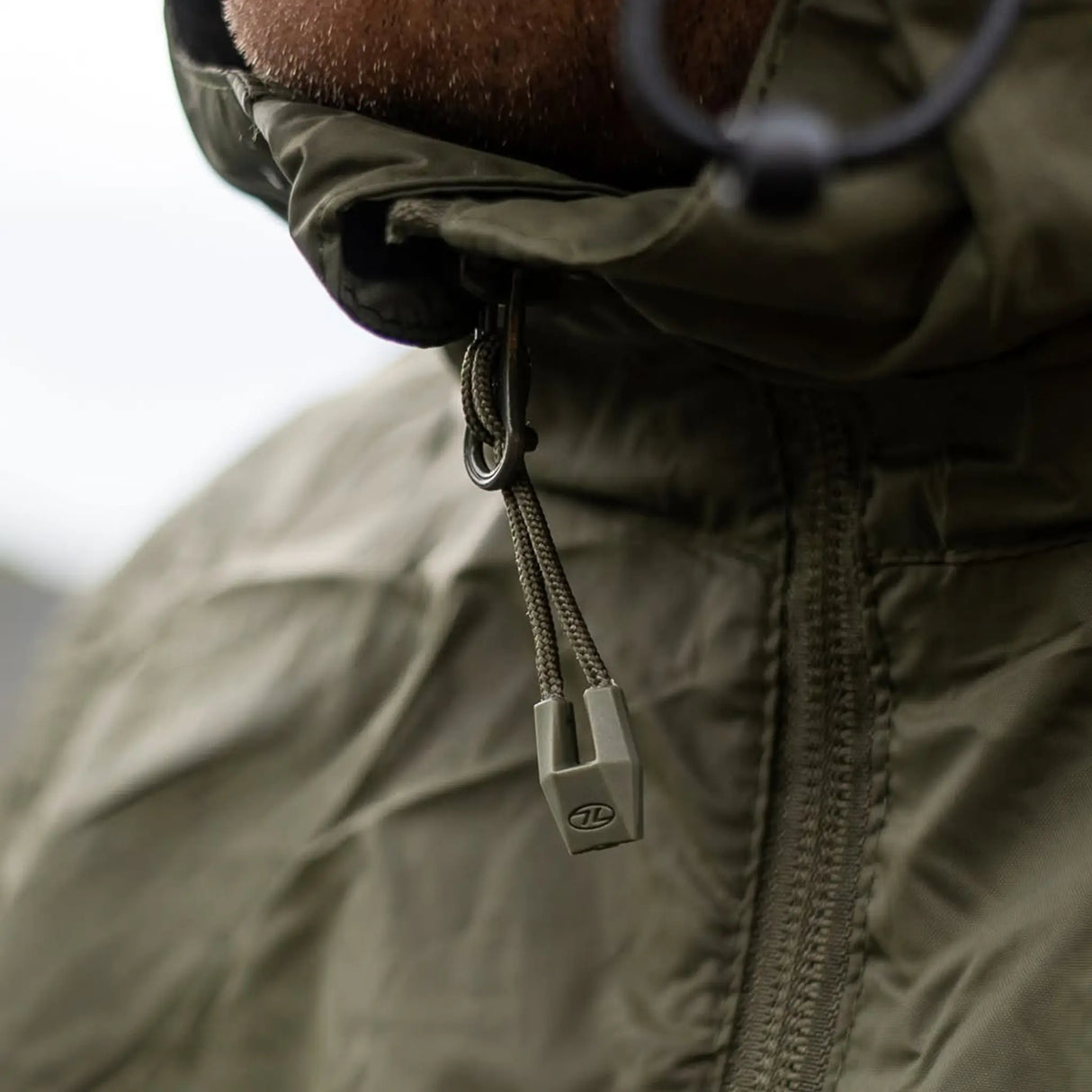 Highlander Stow & Go Pack Away Jacket - close up of zip puller on man in the outdoors