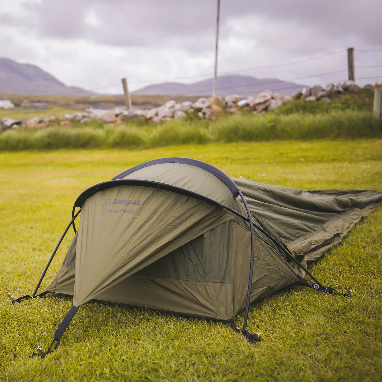 Snugpak Stratosphere WGTE Bivvi Shelter in Olive Green - pitched in a grassy field, front three-quarter view