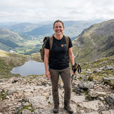 Woman in the Vintage Black Ben Nevis T-shirt with walking poles on a rocky mountain path above a lochan