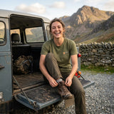 Woman in the Military Green Snowdon T-shirt unlacing muddy boots on a 4x4 tailgate below the mountains