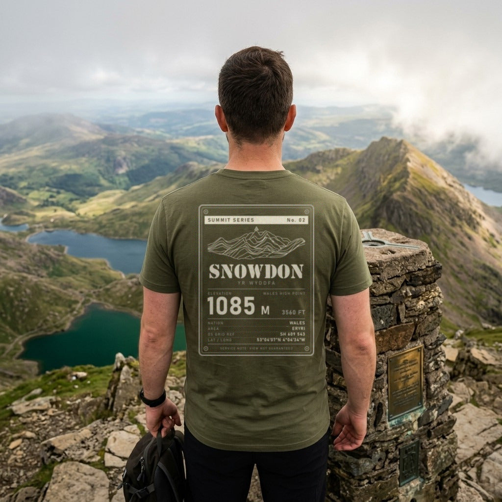 Walker in the Military Green Snowdon T-shirt at the summit trig pillar, showing the 1085 m back print