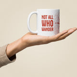 Not All Who Wander White Glossy Ceramic Mug in 11 oz, held in hand, handle on left