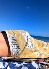 Anorak Tigers Organic Cotton Towel - Ochre and black laid out on the beach