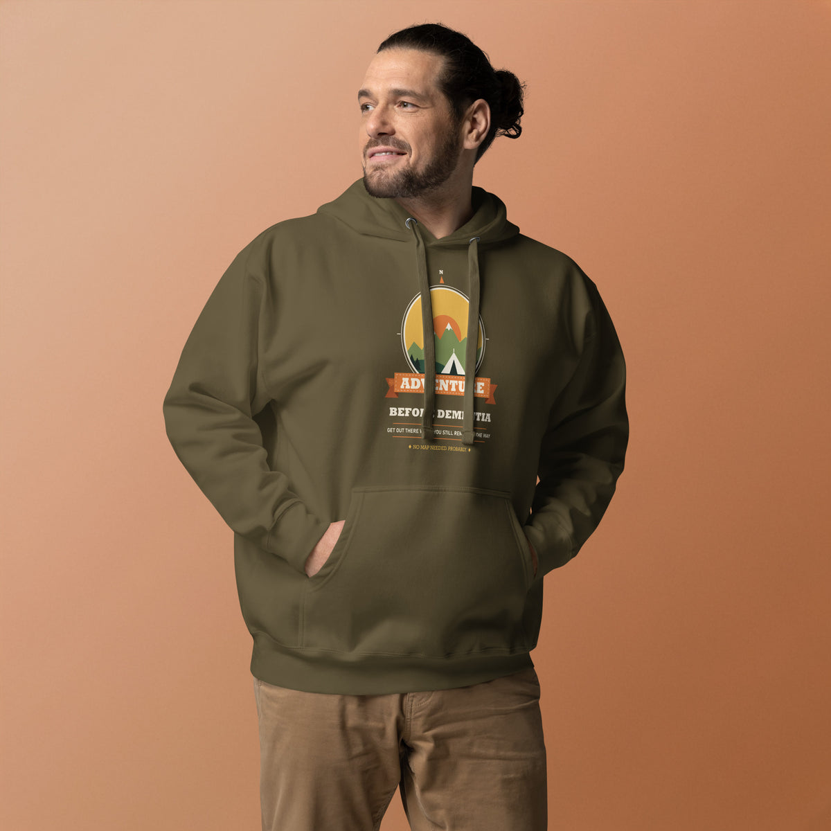 Adventure Before Dementia Camping Hoodie in Military Green, worn by a model against an orange background