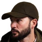 Jack Pyke Wax Baseball Cap in green waxed cotton worn by a model, three-quarter left view showing the curved peak