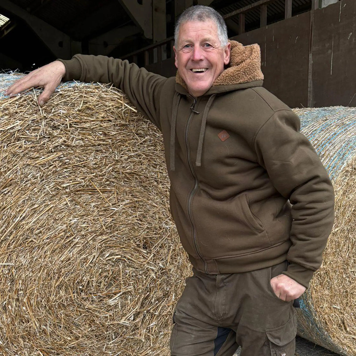 Jack Pyke Yakka Hoodie in olive green on a man working on a farm
