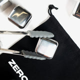 Mini tongs with grey silicone tips holding a Zero Ice stainless steel cube